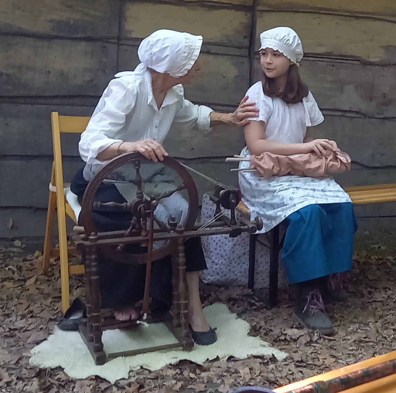 Anne, bénévole Alwati, initie une jeune fille au filage au rouet lors de la fête des charbonniers aux Baraques du 14 - 1er mai 2026